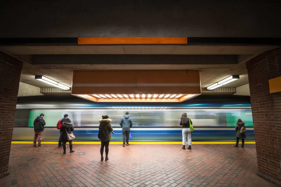 People waiting on subway platform with blurred train passing by.